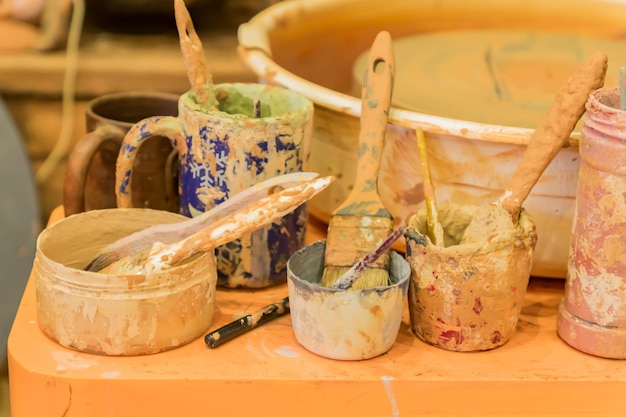 Close up of dirty pottery wheel and colorful mud in jars after work