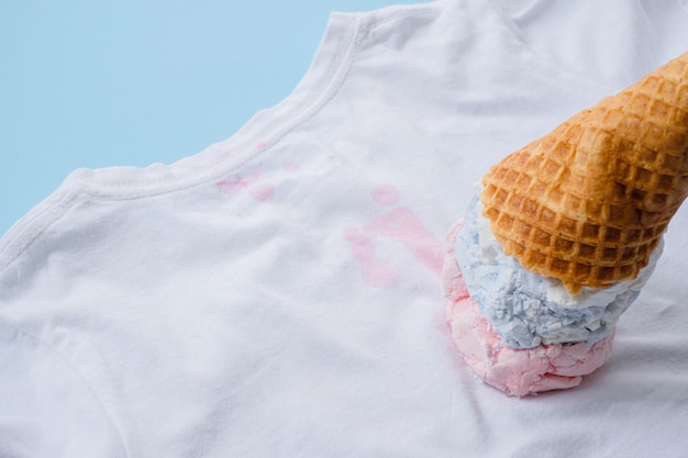 Close up dirty stain ice cream on white clothes on a blue\
background top view daily life stain and