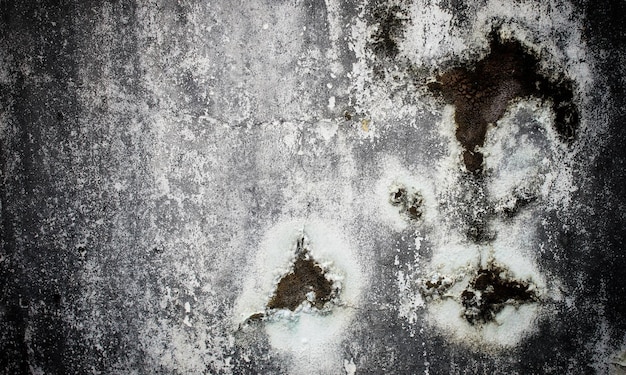 A close up of a dirty wall with a face and a hole in the middle.