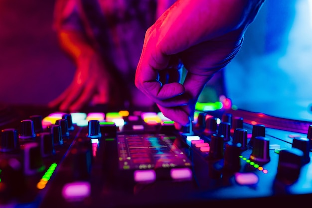 클럽에서 콘서트하는 동안 DJ 콘솔 믹서에서 DJ 손을 닫습니다.