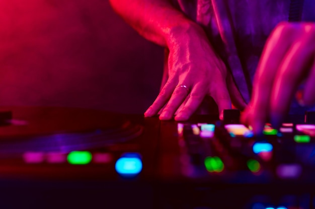 Close up of dj hands on dj console mixer during concert in the club