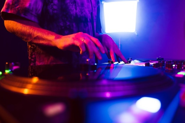 Foto primo piano delle mani del dj sul mixer della console dj durante il concerto nel club