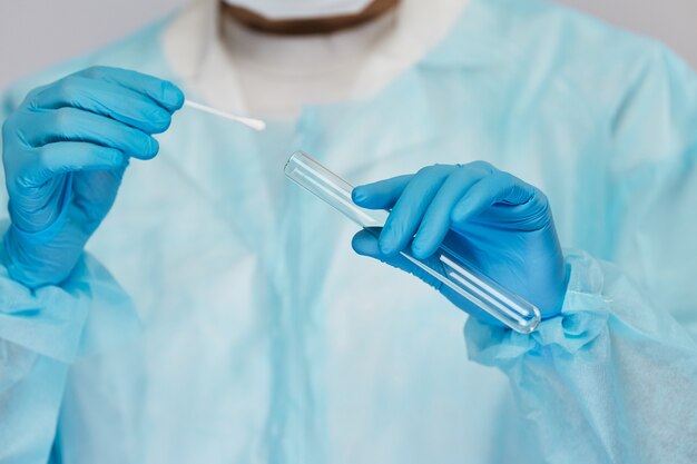 Close-up of doctor arms in blue disposable gloves take samples from the test tube