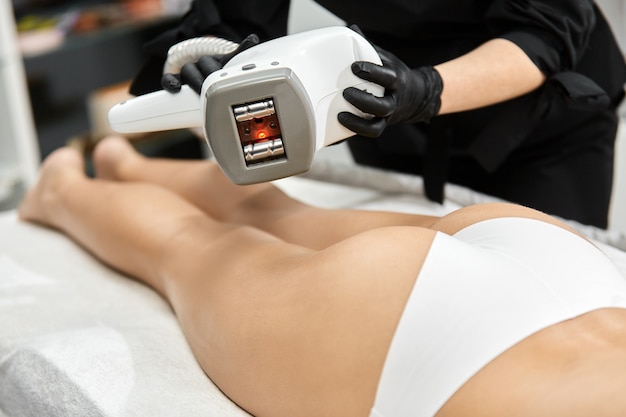 Close-up of doctor arms holding cosmetology device over female body