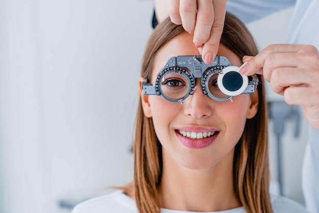 안과에서 시험 프레임으로 여성 환자의 시력을 확인하는 의사의 클로즈업