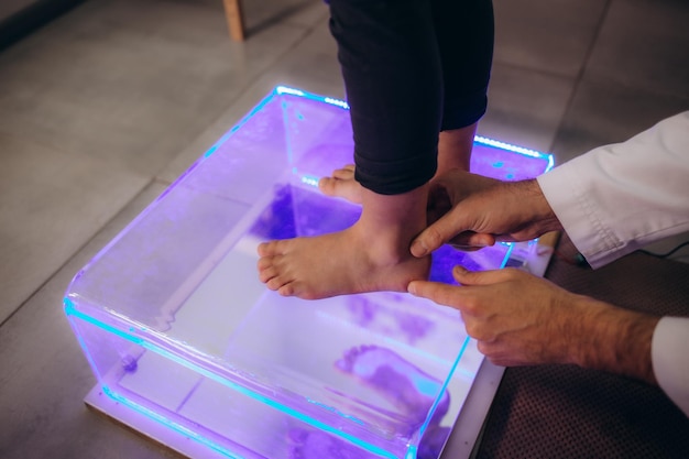 Close up of doctor checks child girl sitting on plantoscope by orthopedist Kids examination flatfoot