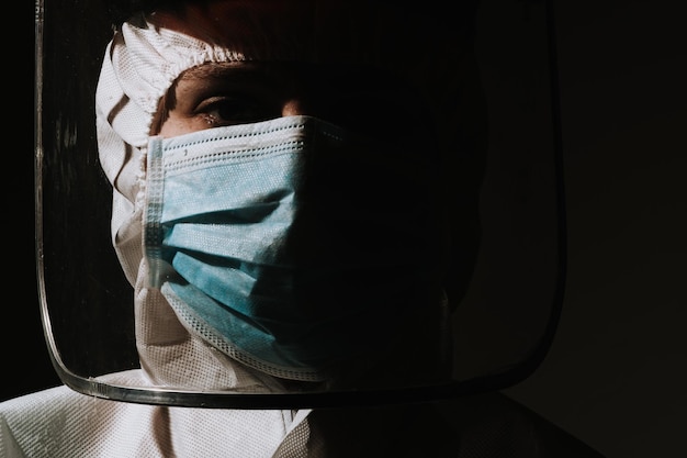 close-up of a doctor crying tear  with mask and face shield due to coronavirus