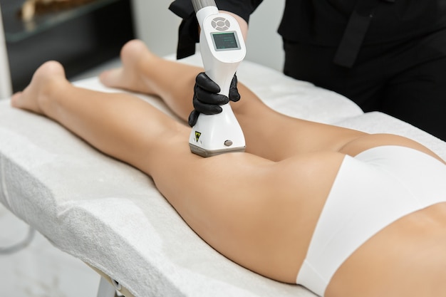 Close-up of doctor doing massage for female legs with lpg massager at professional salon