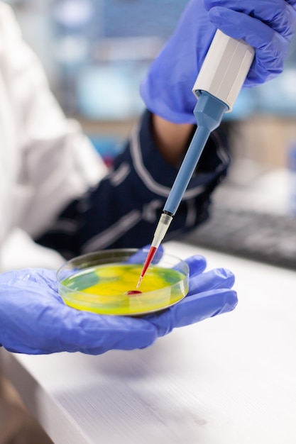 Close up of doctor dropping blood sample using micropipette in medicine lab