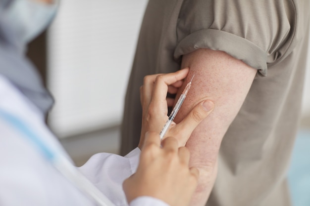 Close-up of doctor giving an injection to patient in his hand