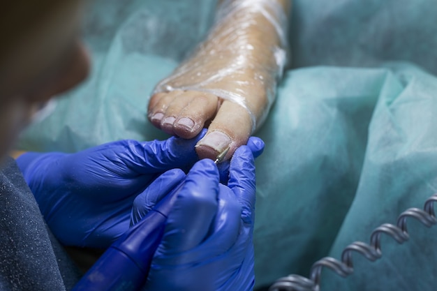 Close up of doctor in gloves making procedure for foot. Pedicure in beauty spa salon.