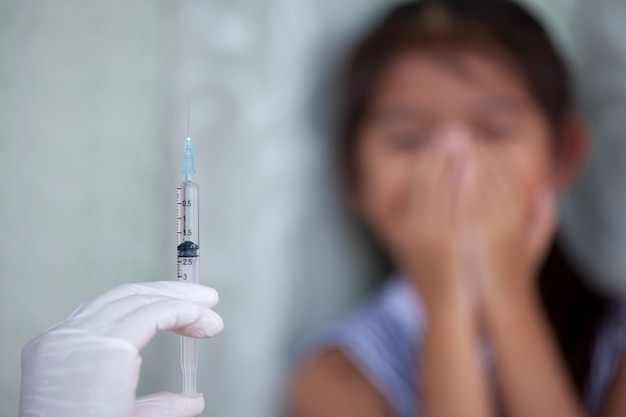 백신 주사 배경을받을 아이 소녀의 두려움으로 의사 손을 잡고 주사기를 닫습니다