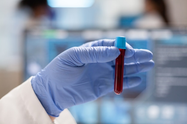 Close up of doctor holding sample of blood in vaccutainer. orolog in professional lab analysing vaccine evolution, using modern technology, epidemics, health innovation.