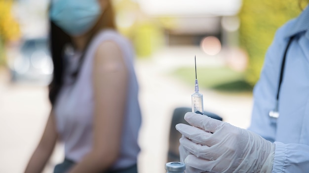 Close up a doctor holding a syringe before injecting the patient wearing a medical mask. Vaccine against COVID-19 or coronavirus