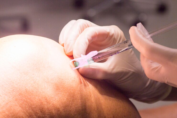Photo close-up of doctor injecting patient on knee
