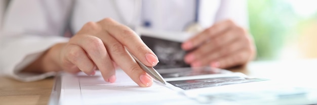 Close up of doctor is engaged in paper work fills in medical records of patients Female doctor analyzes ultrasound images of patients in her office