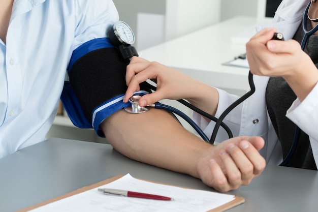 close up doctor measuring blood pressure of her patient