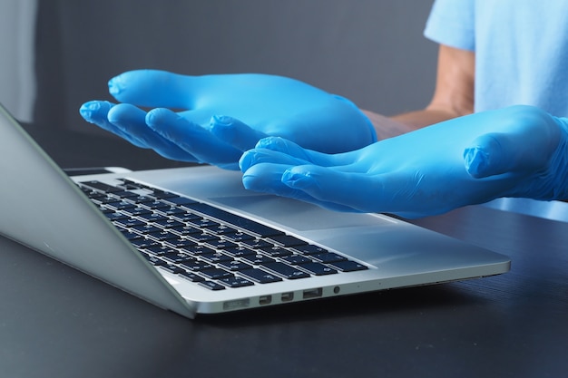 Close-up. Doctor in Medical Gloves for using Laptop. Concept protection from Coronavirus.
