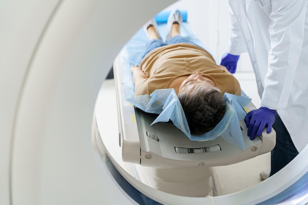 close up of doctor and patient in the room of computed tomography at hospital healthcare concept