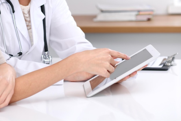 Close up of a doctor and patient sitting at the desk Physician pointing into laptop computer Medicine and health care concept