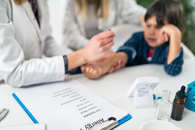 Photo close-up of doctor performing immunology therapy on hand of boy