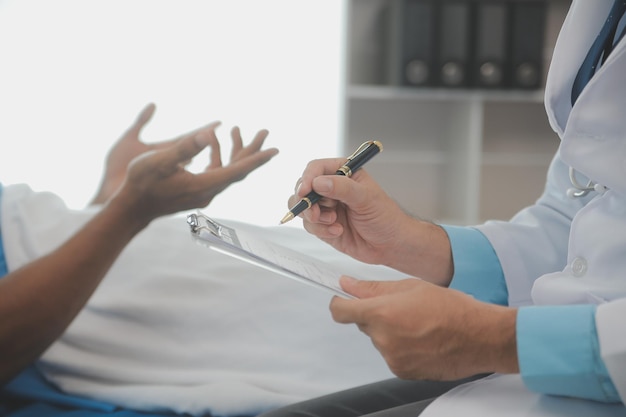 Foto primo piano del medico seduto sul capezzale del paziente maschio in ospedale