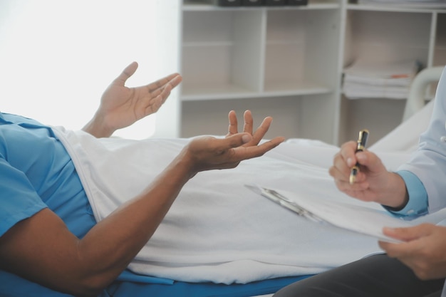 Close up of doctor sitting on bedside of male patient in hospital