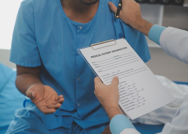 Photo close up of doctor sitting on bedside of male patient in hospital