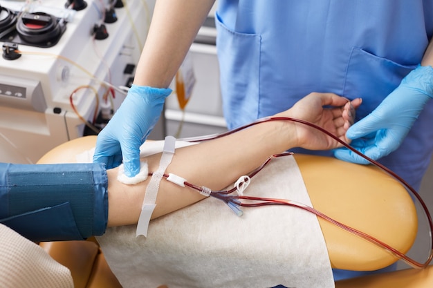 Close-up of doctor taking blood samples from the patient's arm at hospital