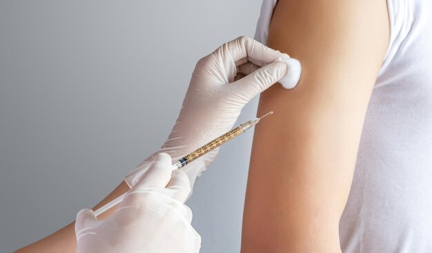 Photo close-up of doctor treating patient by injecting medicine in the upper arm at clinic