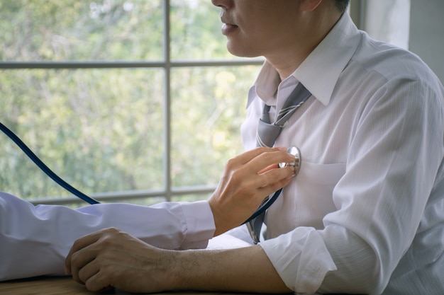 Close up of doctor using stethoscope examining heart