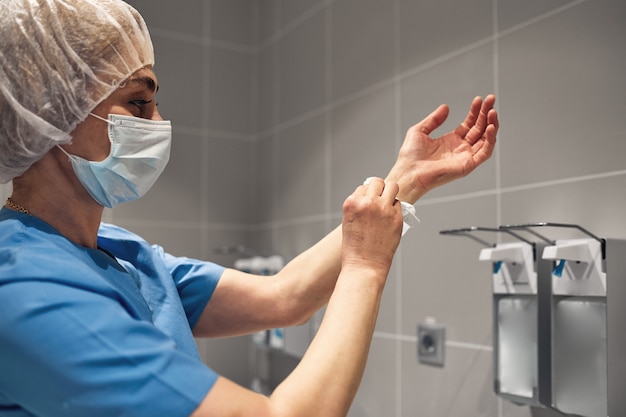 Foto primo piano di un medico che si lava le mani usando un distributore di disinfettante.