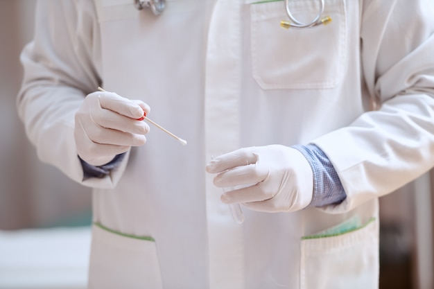 Foto chiuda in su del medico nel tampone bianco della holding dell'uniforme. interno della clinica