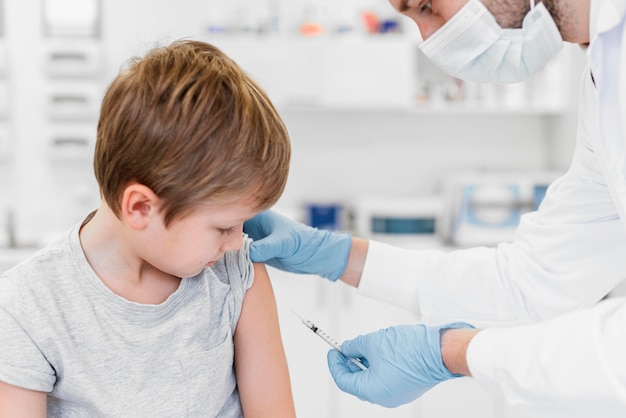 Foto medico del primo piano con la maschera che vaccina il bambino