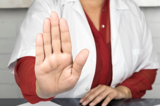 Foto primo piano sul medico con la mano alzata in posizione di arresto