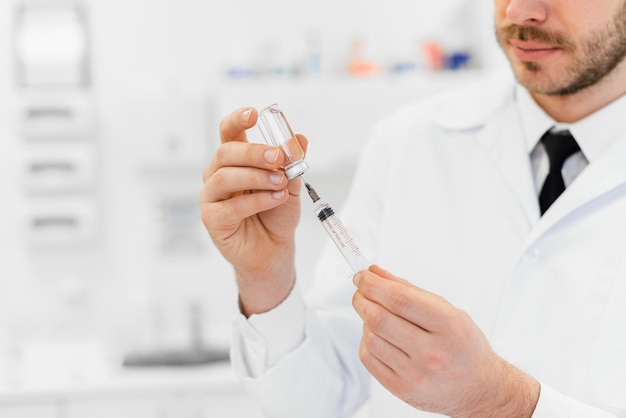 Close-up doctor with syringe and vial