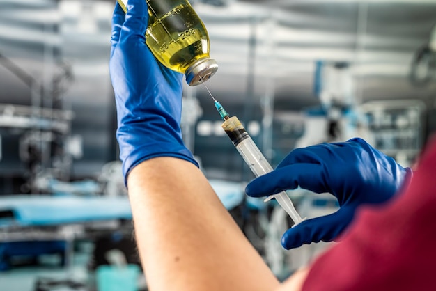 Close up of doctors hand draws the medication or anesthesia from a glass vial with a syringe