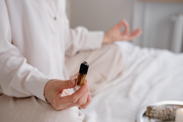 Foto close-up doet ochtendmeditatie na het ontwaken thuis vrouwelijk model zit met de benen gekruist en mediteert