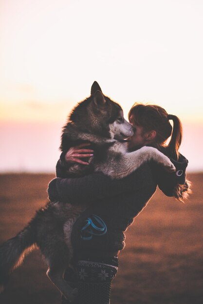 Photo close-up of dog on beach against sky during sunset