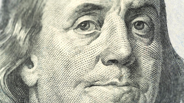 A close up of a dollar bill with the face of a man looking at the camera.