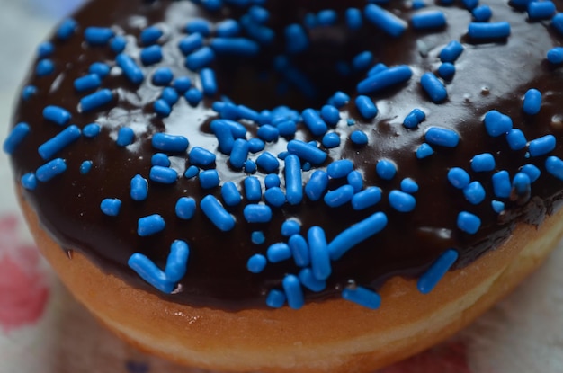 Photo close up of donut with chocolate icing and blue candy sprinkles