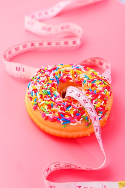 Close up of donuts and measurement tape on pink space.