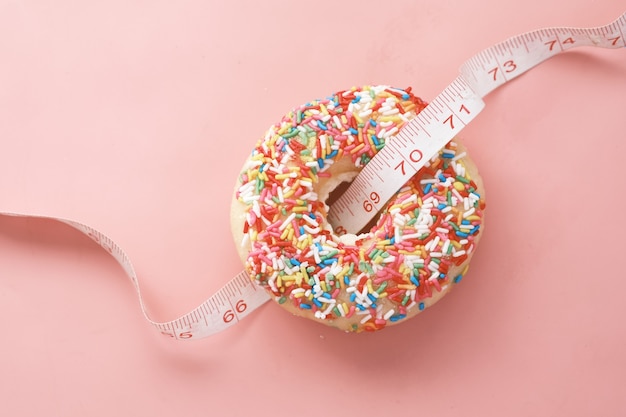 Close up of donuts and measurement tape on pink surface