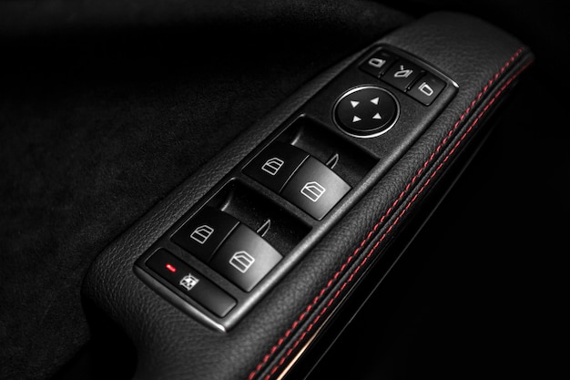 Close up of a door control panel in a new modern car. Arm rest with window control panel, door lock button, and mirror control.
