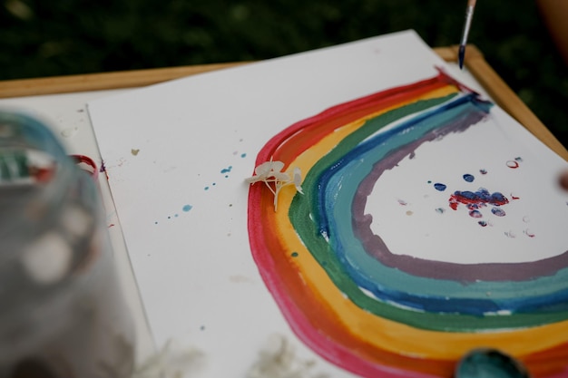 Photo close up drawing of child with paints outside in the garden.