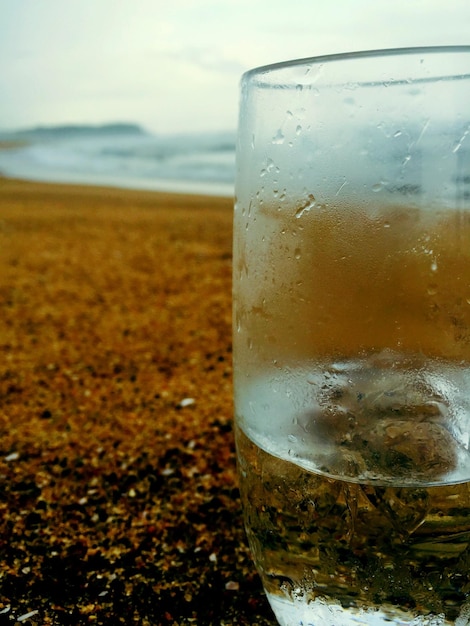 Foto close-up di una bevanda in bicchiere sulla spiaggia contro il cielo