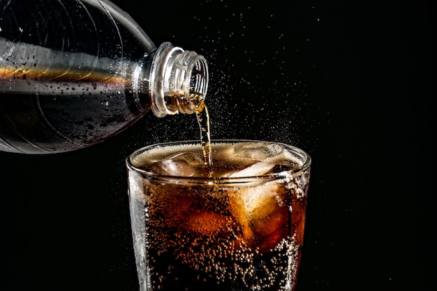 Photo close-up of drink pouring in drinking glass against black background