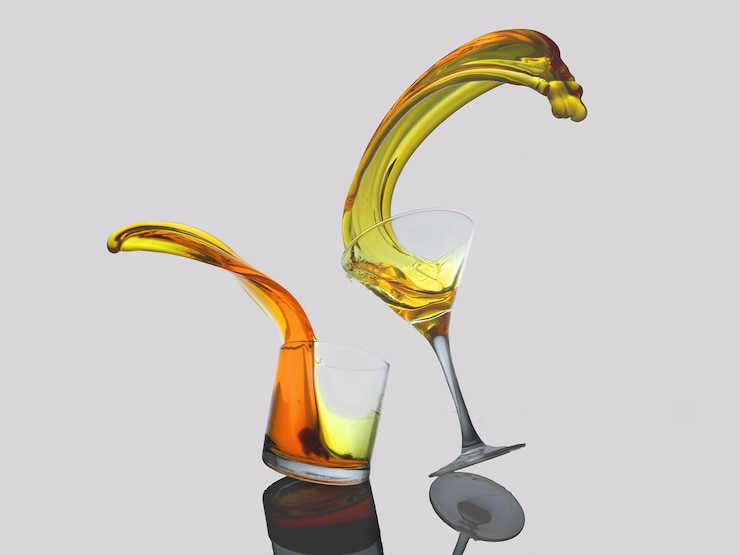 Photo close-up of drink spilling from glasses against white background