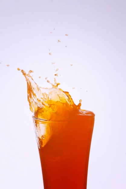 白い背景の上でボトルから飲み物が飛び散るクローズアップ