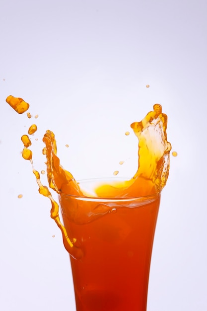 白い背景の上でボトルから飲み物が飛び散るクローズアップ